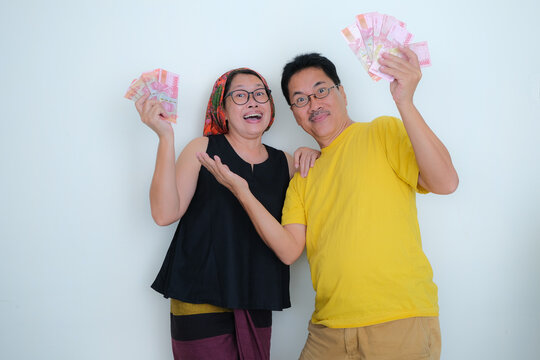 Husband And Wife Standing, Looking Happy With Lots Of Cash Money In Their Hands