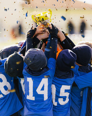 Boys in blue winter soccer jersey shirts rising golden trophy at champions ceremony. Kids in winter...