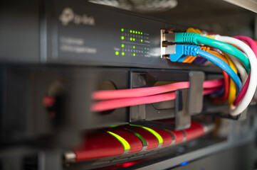 Router and switch with colorful LAN cables in a network cabinet of a data center