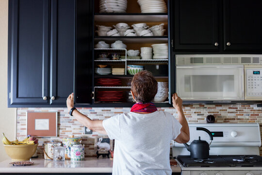 Rear view of woman checking cabinet in kitchen