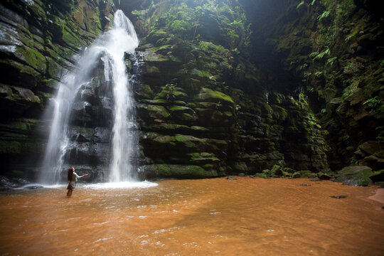 A woman observes a waterfall in Brazil.
