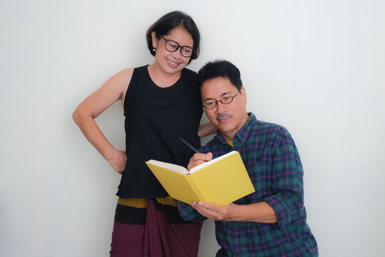 Husband and wife taking notes on a yellow book together