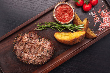 Fried meat steak with slices of fried potatoes with sauce, coarse salt and tomatoes