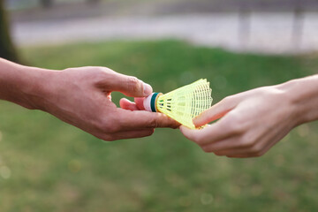 The young couple is holding shuttlecock for badminton in green park