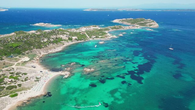 Windsurfer sails at turquoise blue sea along coastline of La Maddalena Island, Sardinia - Aerial
