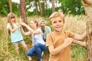 Fototapeta premium Boy collecting wood while camping with family in forest