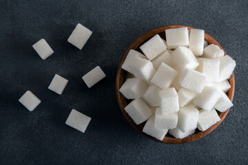 White sugar cubes in bowl on a dark background