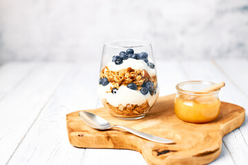 Healthy food concept. Homemade granola with nuts and honey in a glass with yogurt and fresh berries for breakfast. Vegetarian food.