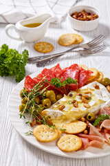 savory baked brie with crackers, salami, nuts, ham
