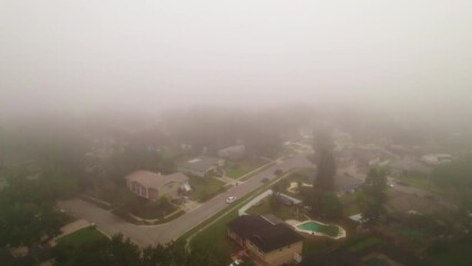 Aerial reverse flyover through foggy and misty neighborhood in city of Ocoee, Florida with no vehicles driving.  Ocoee is a family oriented town with many neighborhoods.