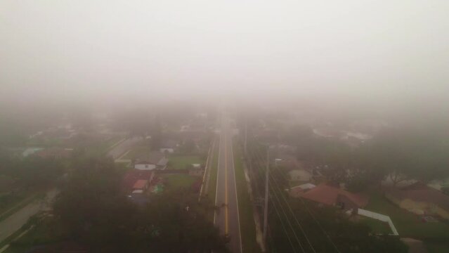Aerial flyover of foggy and misty road through city of Ocoee, Florida with no vehicle driving.  Ocoee is a family oriented town with many neighborhoods.