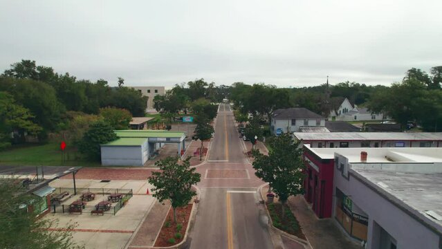 Reverse aerial flyover of the empty and abandoned downtown area of Ocoee, Florida with nobody and no vehicles.  Ocoee is a family oriented town with restaurants, breweries, bars, and shopping.