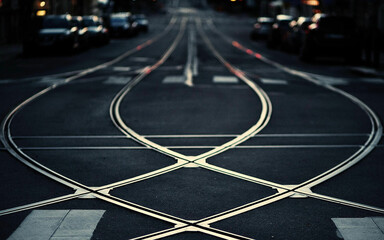 Photo of crossed white steel railroad tracks on the road paved with black asphalt with black...
