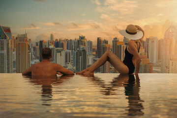 couple enjoying Dubai skyline with skyscrapers architecture from hotel infinity pool at sunset....