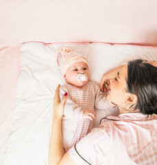 mom hugging baby lying on bed, top view, enjoying parenthood,baby at home