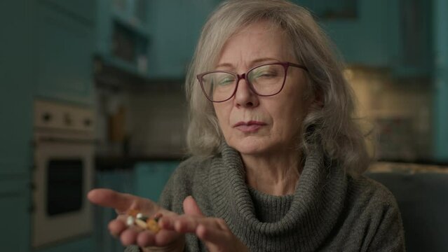 60s Woman Counting Pills On Hand. Senior woman taking care of health.