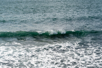 Fototapeta premium The waves of Black Sea run to seashore. Waves of the traditional color of the sea wave blue, turquoise, green, gray as an ideal background for theme of relaxation. Elegant nature concept for design