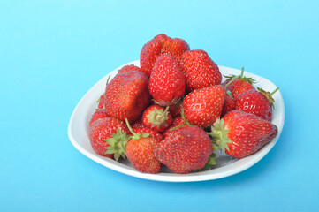 Strawberries on a plate on a blue background