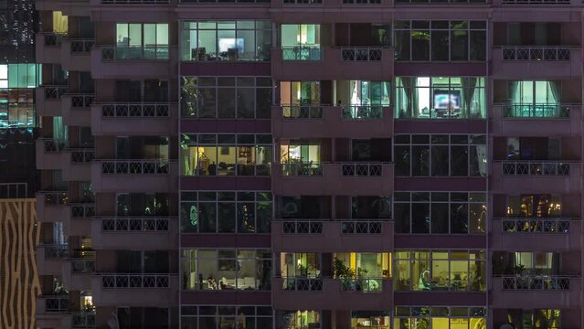 Flat night panorama of multicolor light in windows of multistory apartment buildings aerial timelapse. Illuminated skyscraper in a big city