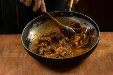 The cook prepares meat with vegetables and onion in a bowl . Oriental cuisine