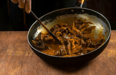 The cook prepares meat with vegetables and onion in a bowl . Oriental cuisine
