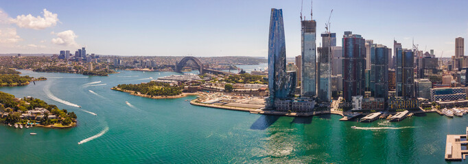 Naklejka premium Panoramic aerial drone view of Barangaroo waterfront precinct in Sydney City, NSW showing Barangaroo Reserve and the Harbour Bridge on a sunny day 