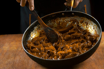 The cook prepares meat with vegetables and onion in a bowl . Oriental cuisine