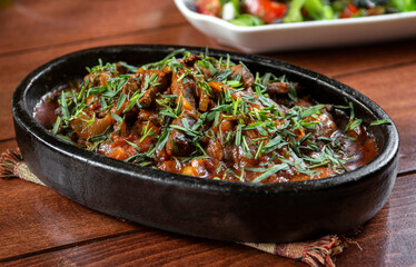 Oriental cuisine:  meat with vegetables and onion in a bowl close-up on the table.