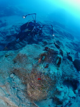scuba diver underwater exploring and taking photos of ancient amphoras deep water history search