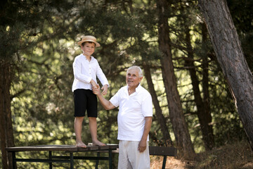 Naklejka na ściany i meble Happy senior man Grandfather with cute little boy grandson playing in forest