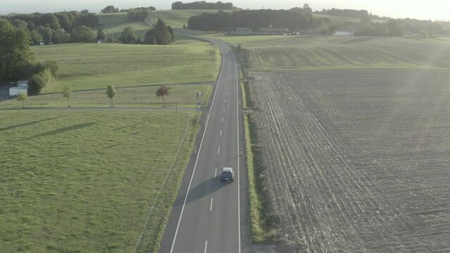 Car driving on rural road in a field in D-LOG ungraded