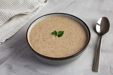 Homemade Cream of Mushroom Soup in a Bowl on a gray background, side view.