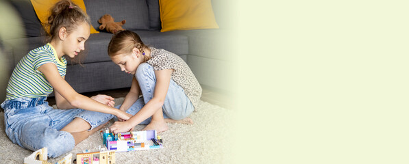 Russia, Krasnodar 12.18.2022 Two little sister girls play with multi-colored toy blocks at home in...