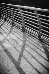 Black and white image of bridge handrails with hard shadow.