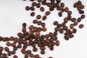 Coffee beans are scattered on a white table. photo of freshly roasted coffee close-up of high quality. top view