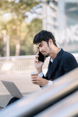 pleasant looking successful professional male business accountant learns clients case, works on modern laptop and smartphone, Drinking Coffee from a Mug.