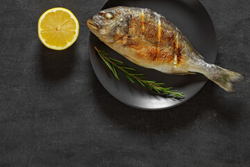 Dorado, cooked, grilled fish source of omega 3, rosemary, lemon on dark background, top view, space...