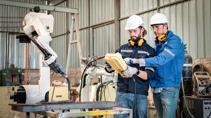 Engineer factory industry wearing safety uniform work and checking system of the welding robots for welding steel electrical control system is robot automate for industry manufacture concept.
