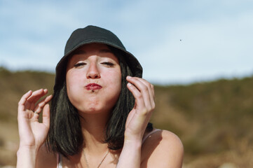 portrait of young tourist woman on the mountain looking at the camera with inflated cheeks.