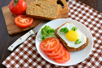 healthy sandwich with fried egg and yellow yolk on plate isolated with vegetables