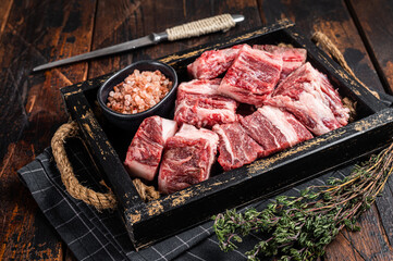 Uncooked Raw diced cubes of lamb meat in wooden tray with salt and thyme. Wooden background. Top...