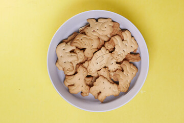 animal shape sweet cookies in a white bowl yellow background 