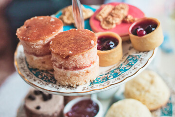 High tea with ceramic tiered plate stand with scones, cupcakes and mini jam tarts at a kid's...