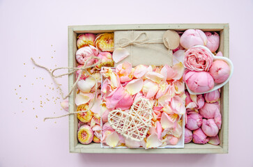 Gift box and rose buds and petals. Fresh flowers, craft gift, straw tangled heart. Roses in a box pink roses, yellow roses. Fashion. Minimalism. Valentine's Day, wedding concept