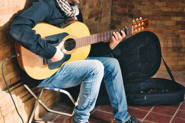A male busker playing Spanish acoustic guitar with a small amplifier in the street