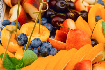 Fruit and berry assortment of slices of peaches, apples, oranges, apricots and blueberries; juicy vegetarian salad, diet and healthy food