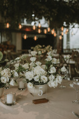 White flowers on gray tablecloth with candles, cutlery and menu. Wedding decoration.