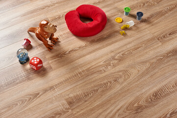 Scattered children's toys on the wooden floor, young children's play set, plastic dinosaur, colorful art plasticine and neck pillow