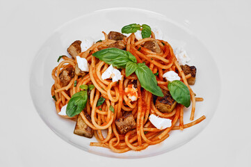 Portion of pasta with tomato sauce, slices of roasted eggplant, soft white cheese and basil leaves, vegetarian dish of traditional Italian or Mediterranean cuisine