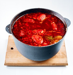 Large pot of traditional borscht soup on wooden board, delicious hot lunch dish of beets and assortment of vegetables for vegetarians